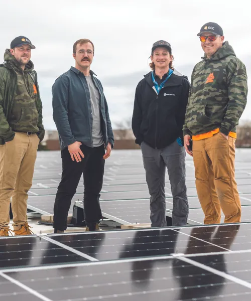 Four men standing among solar panels