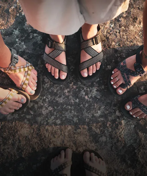 Four pairs of feet wearing sandals outside 