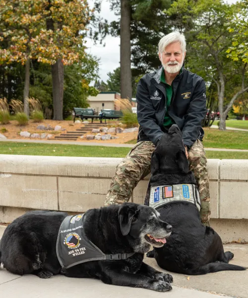 Veteran Services Director sits outside with his two support black labs