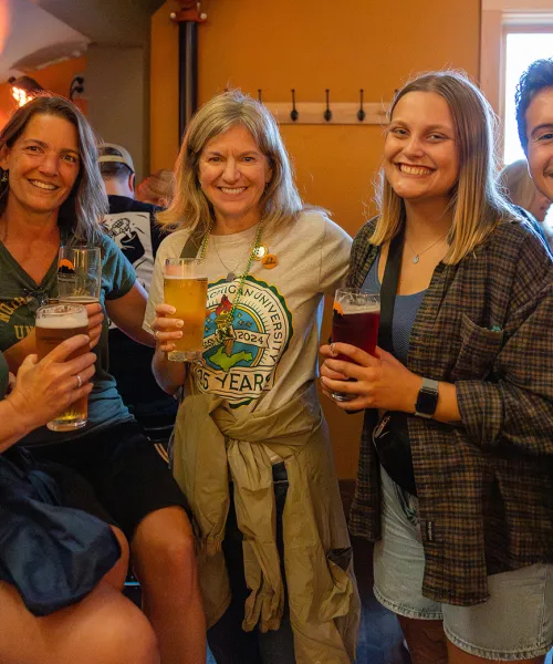 Five alumni of all ages with pints of beer