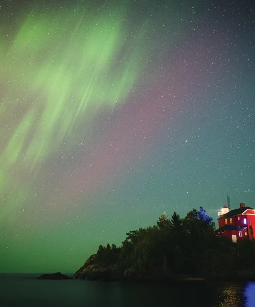 The Northern Lights shining in the sky over Marquette Harbor Lighthouse.
