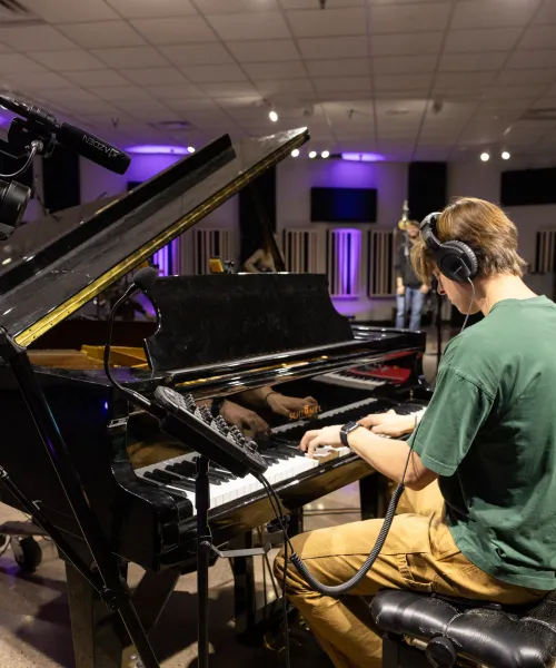 A NMU student playing a piano in a recording studio.