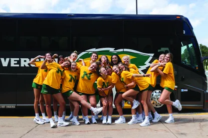 Women's Volleyball team outside their bus