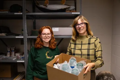 Two young women with box of antiques in storage room