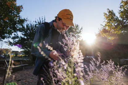 An NMU student smelling the flowers in the Eco Park on NMU's campus