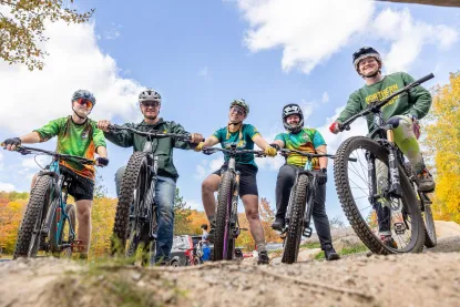 Five smiling students on mountain bikes looking at the camera.