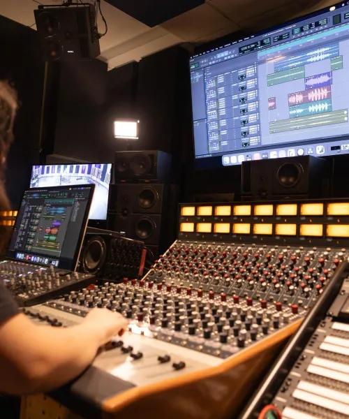 A NMU student working at a mixing console in a recording studio.