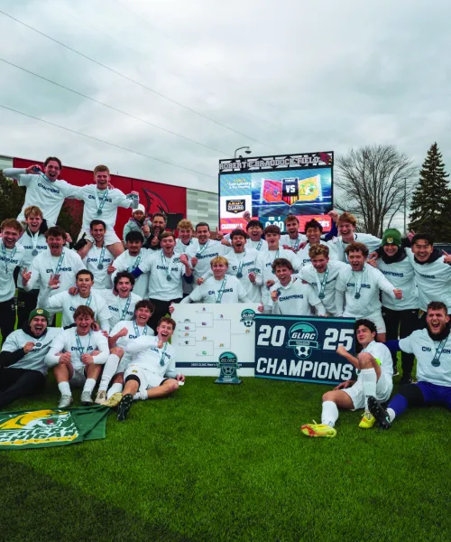 NMU's Men's Soccer team holding the 2025 GLIAC Championship banner.