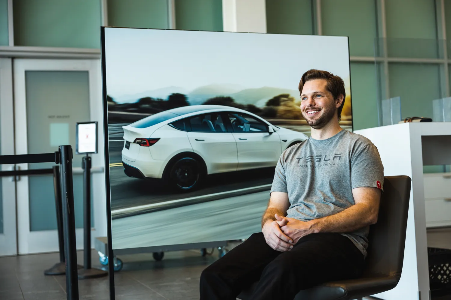 Tyler Amond in front of a photo of a Tesla car