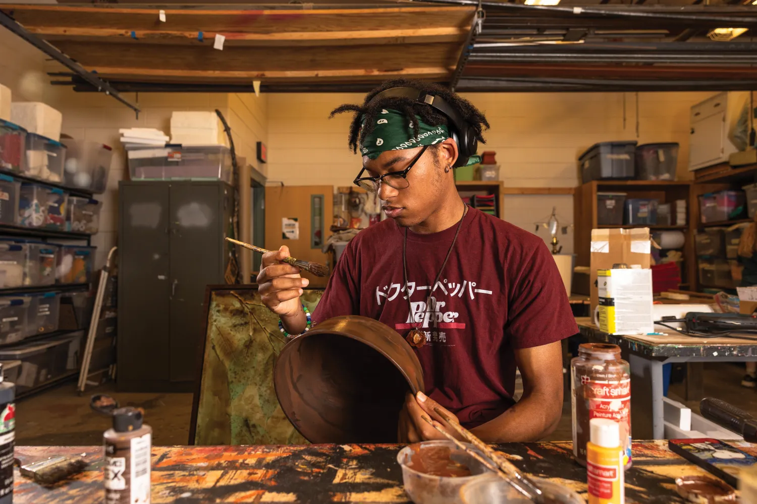 Student painting bowl in scene shop