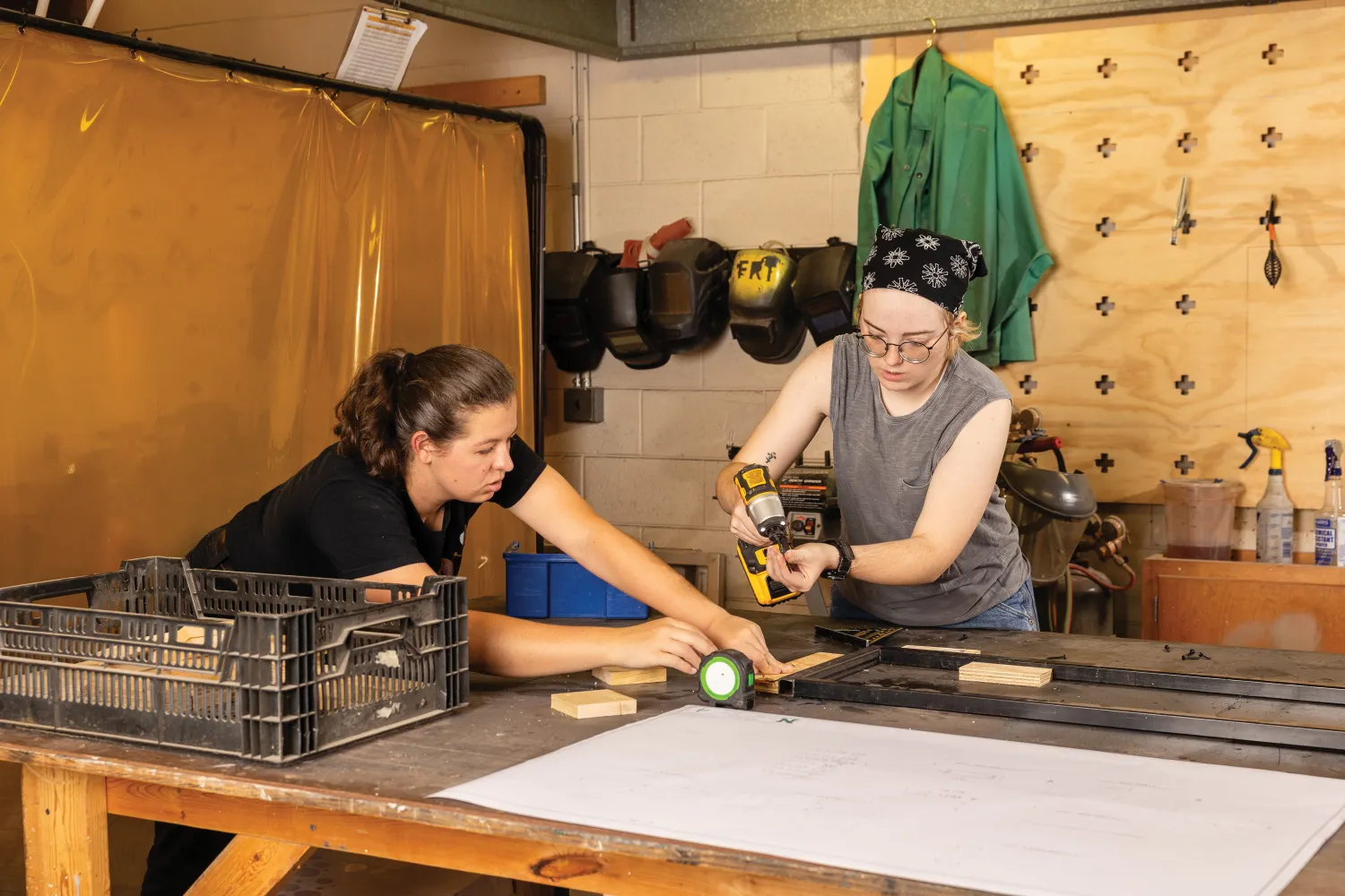 Student and teacher working with drill and wood in set shop.