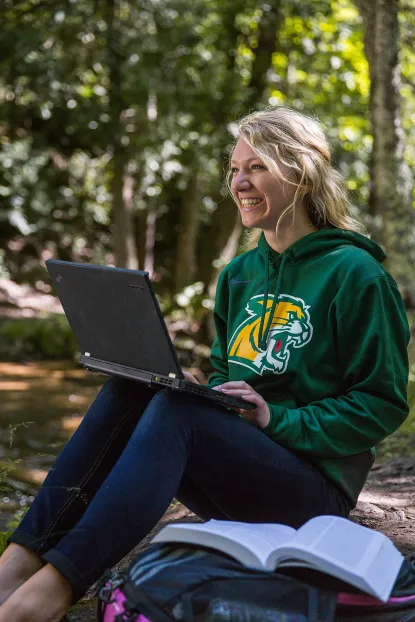 Female student on laptop in the woods