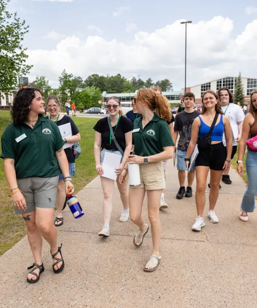 Two students leading a group of students and family on a campus tour at NMU