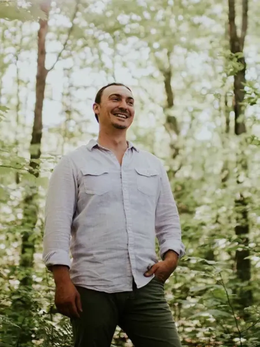 Tyler Dettloff standing amongst trees with leaves