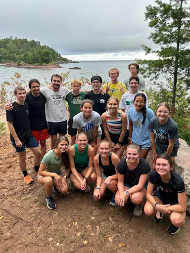 Team photo with lake in background during a run.