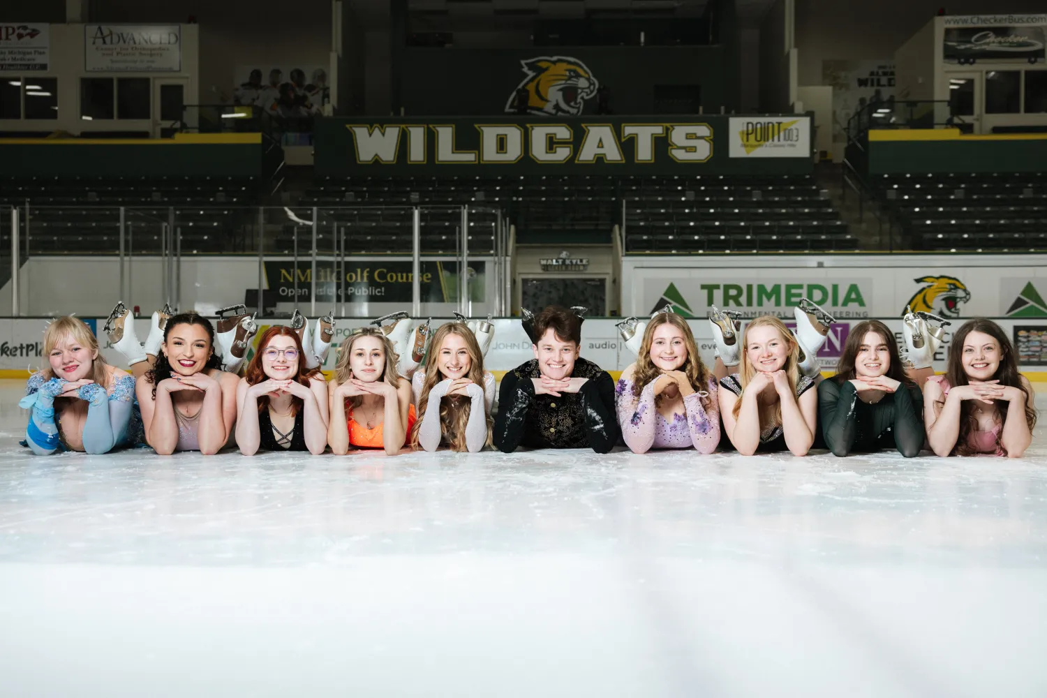 Ten skaters laying on ice in pose for a photo
