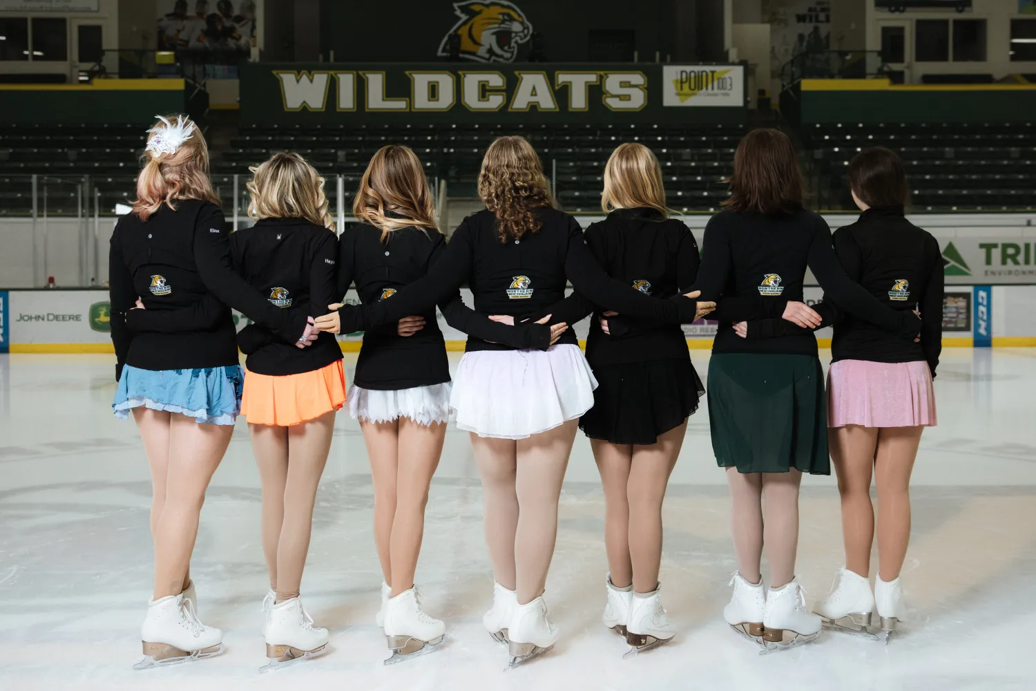 Seven members posing in performance wear from backside