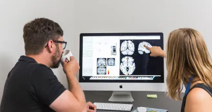 Male faculty member and female student looking at brain scans on a computer
