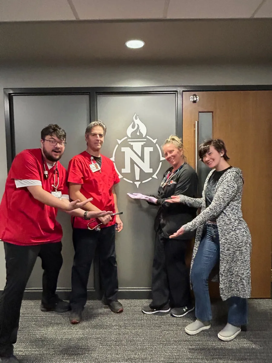 NMU nursing students in front of NMU torch logo