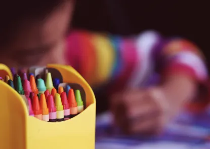 Photo of crayons with child coloring in the background