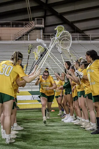 Photo of Taylor running between her teammates holding a lacrosse stick