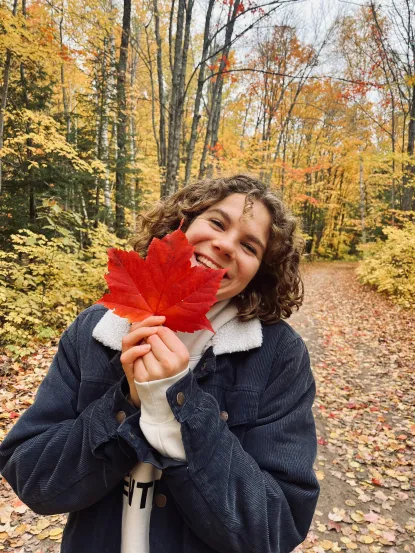 Image of a girl smiling holding a red leaf