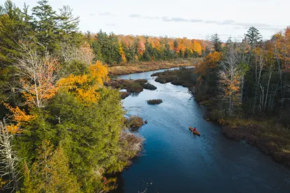 Researcher canoeing down a river in the fall