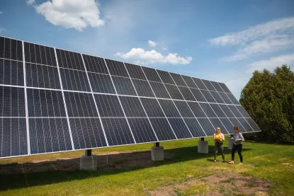 Two people walking next to solar panels