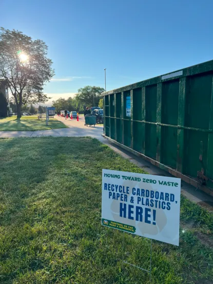 Dumpster with sign that says "recycle cardboard, paper, and plastics here"