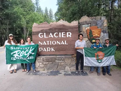 Slippery Rock Team standing in front of Glacier National Park sign