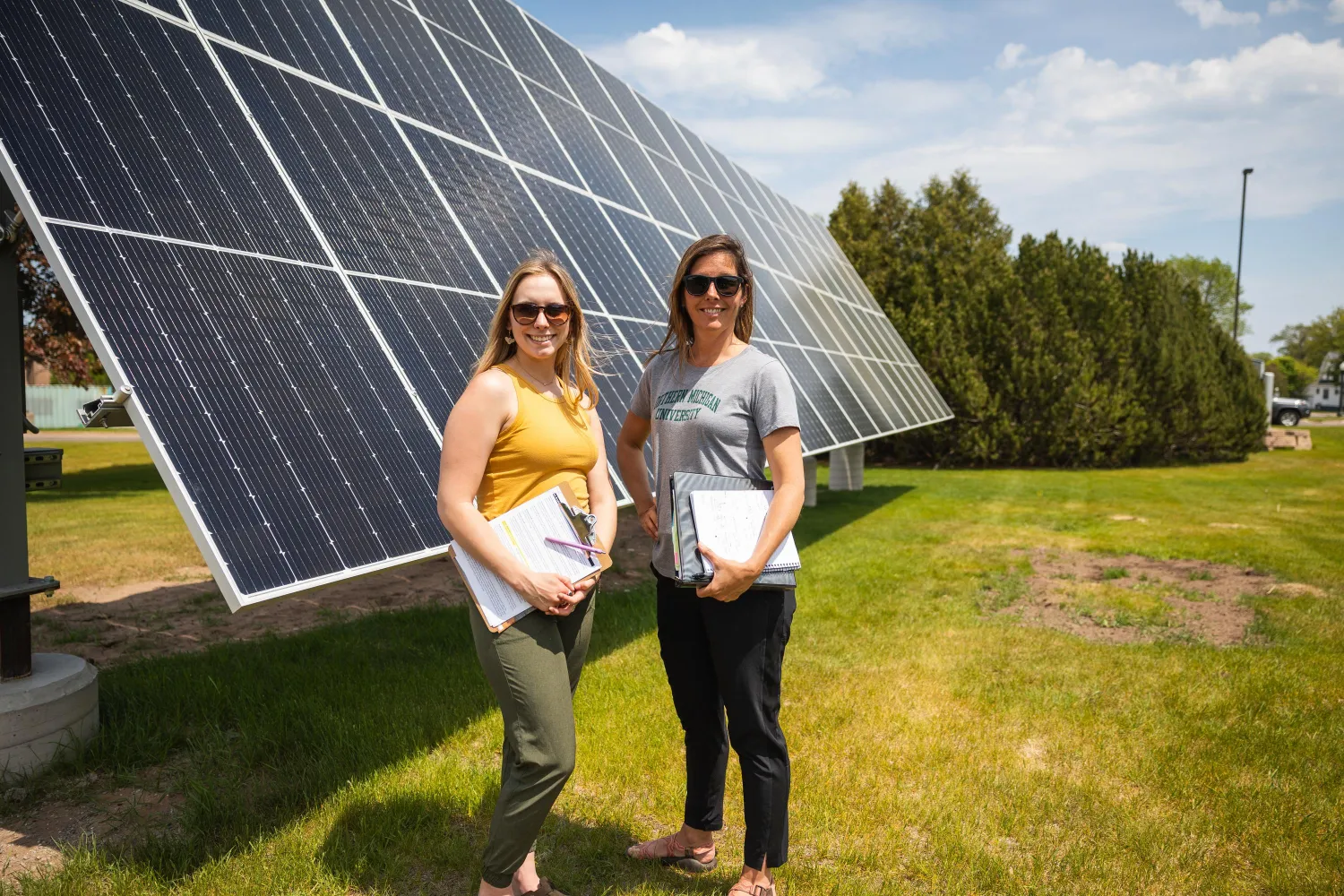 two women standing in front of solar panels 