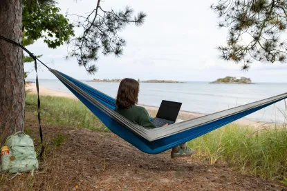 A student using a laptop while sitting in a hammock near Lake Superior.