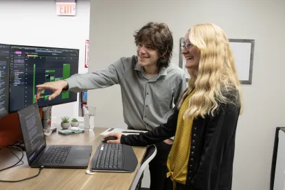 A student working at a computer with a coworker during an internship
