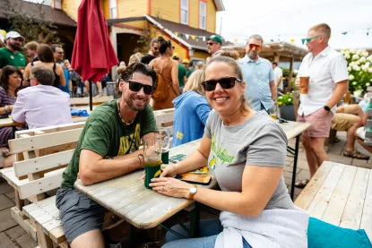 Two NMU alums sit at a picnic table during an alumni event.