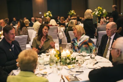 A group of people sit at a table, talking during a NMU Foundation event at the Northern Center.