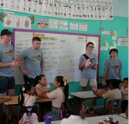College students teaching to children in a Belize classroom.