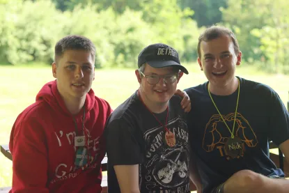 Three men pose with green trees in the backgroud.