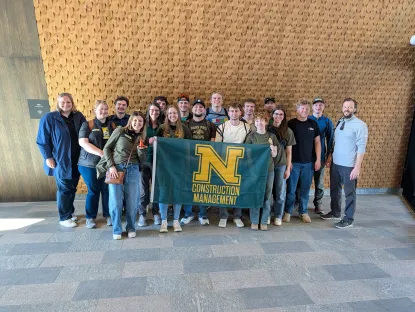 Group of NMU construction management students an faculty pose with a flag in Norway.