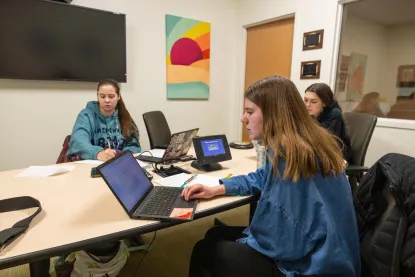 Three NMU social work students work together with laptops and notes in the Social Work Observation Lab.