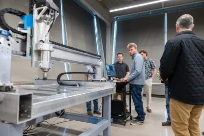 NMU engineering students work with a large automated machine in a lab.