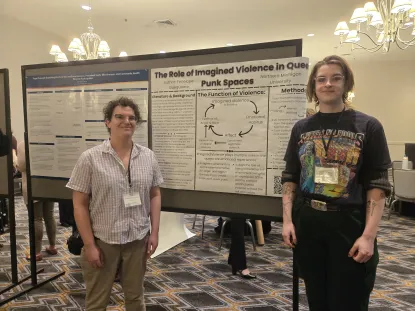 Two women stand in front of a poster on a poster board.