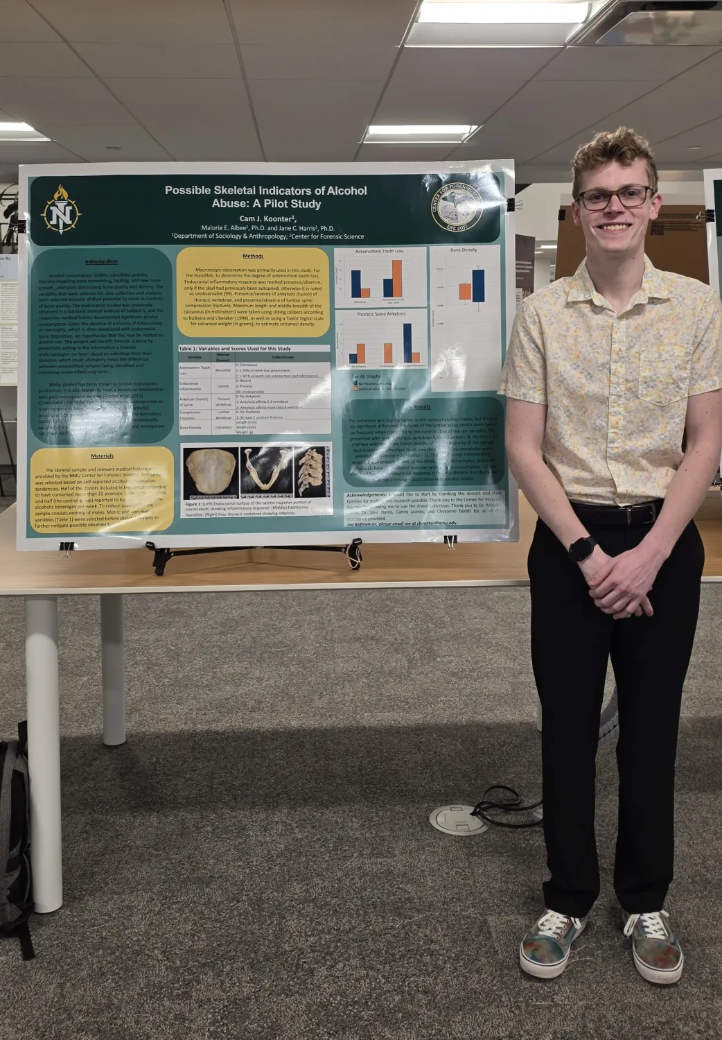 A male student standing next to a poster