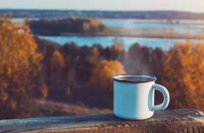 Coffee mug sitting on deck in fall with the lake in the background