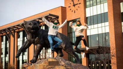students jumping in front of the wildcat statue