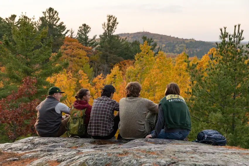 A group of NMU students looking out at the fall colors at the top of Mount Marquette.