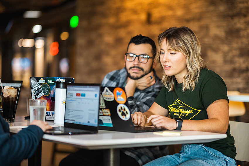 Two NMU students at a local restaurant working together on a laptop computer.