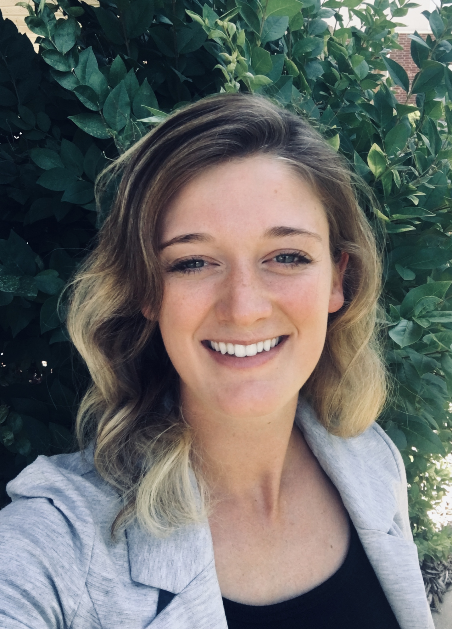 Woman with dark green leaves behind her.