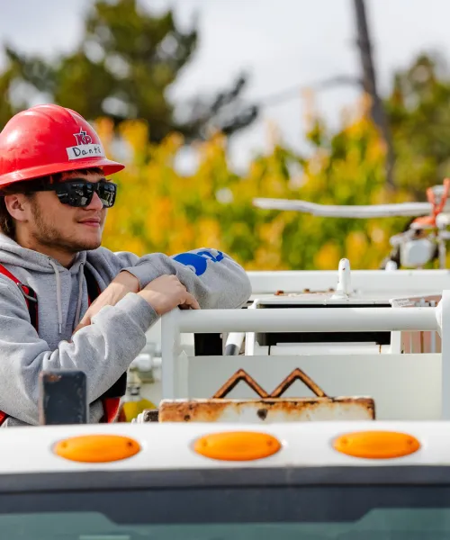 Student in red hard hat leaning on truck