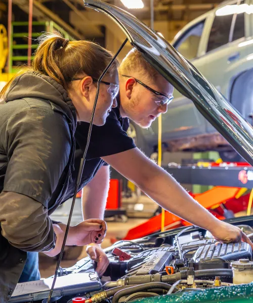 one female and one male student working on car