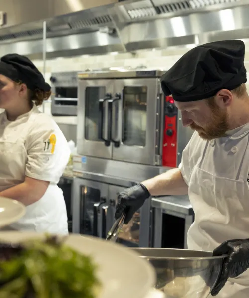 Students work on the line during restaurant service, portioning salads